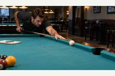 Pool player testing cue-ball speed, cushion response and pocket entry on an unfamiliar worn table