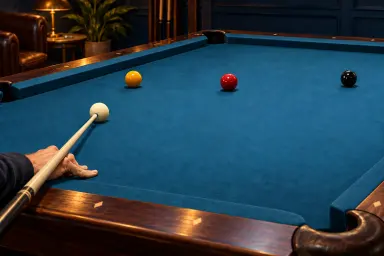 Anonymous hand holding an ordinary cue beside one white cue ball and colored object balls on a clean table