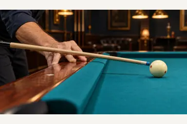 Editorial side view of a pool player anchoring a bridge hand on the wooden rail with the cue supported above the cushion
