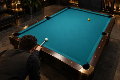 Anonymous player and two resting balls on an unmarked six-pocket pool table